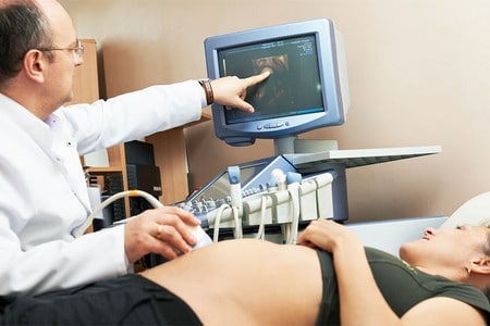 Доктор проводит обследование организма беременной женщины