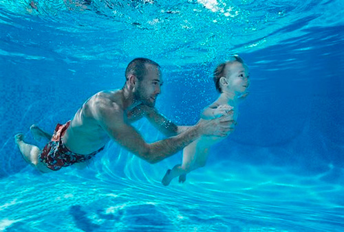 Папа с малышом ныряют в бассейне