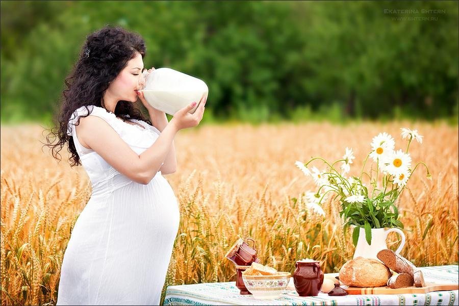 Красивая беременная женщина на пшеничном поле кушает