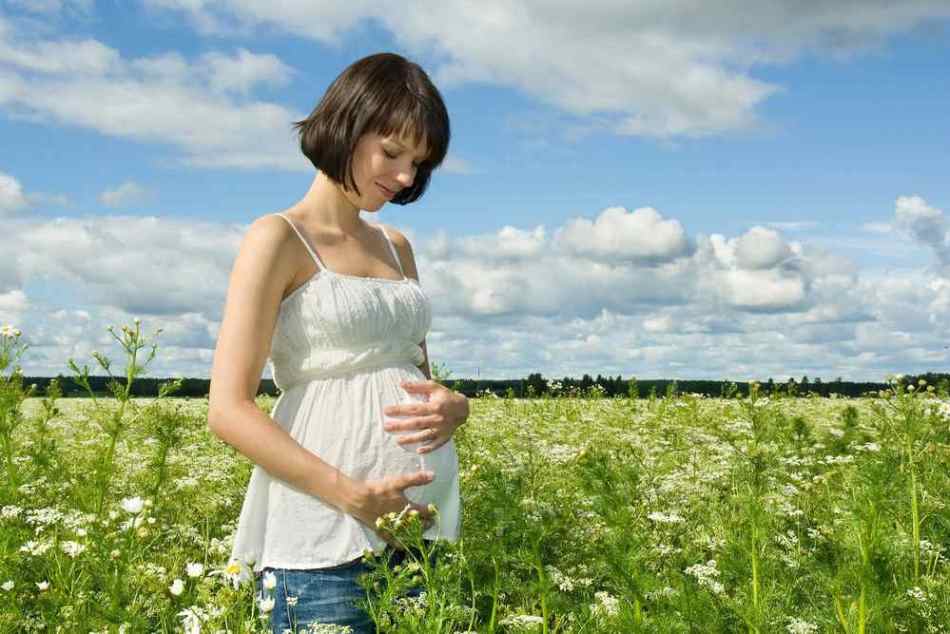 Счастливая беременная девушка гуляет по лугу