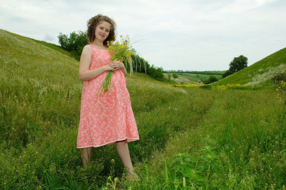 Счастливая беременная девушка собирает травы и не страдает циститом