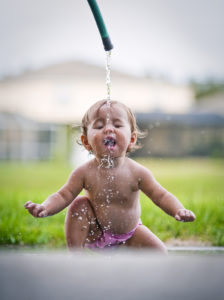 ребенок пьет воду из шланга
