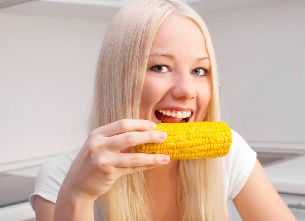Девушка ест вареную кукурузу