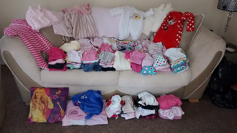 вещи для новорожденного, разложенные на диване