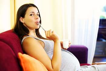 Беременная женщина ест йогурт