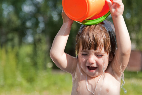 Ребенок обливается водой из ведерка